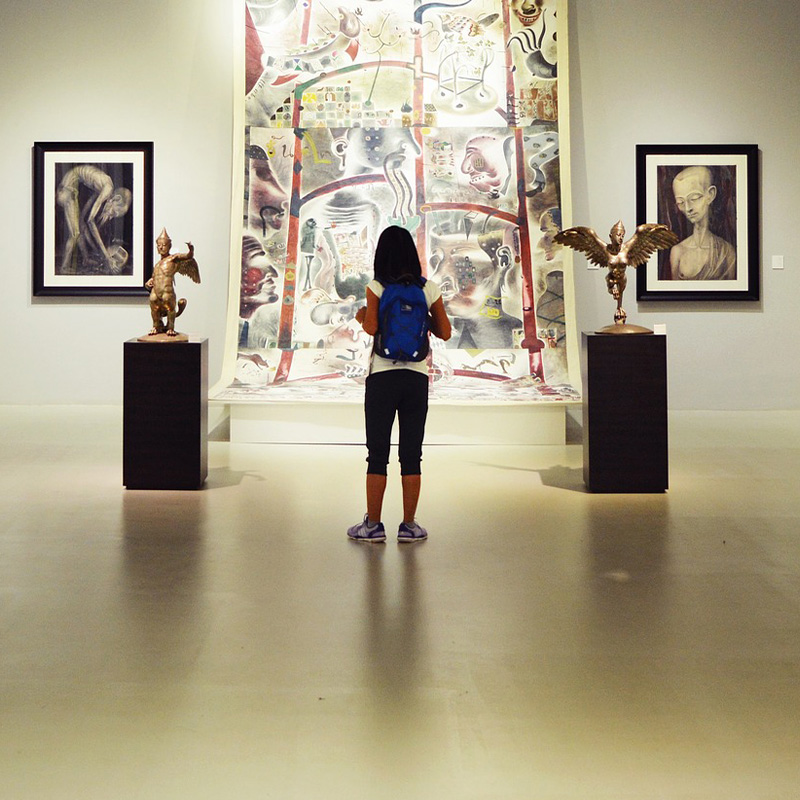 a girl in a museum stands in front of a work of art